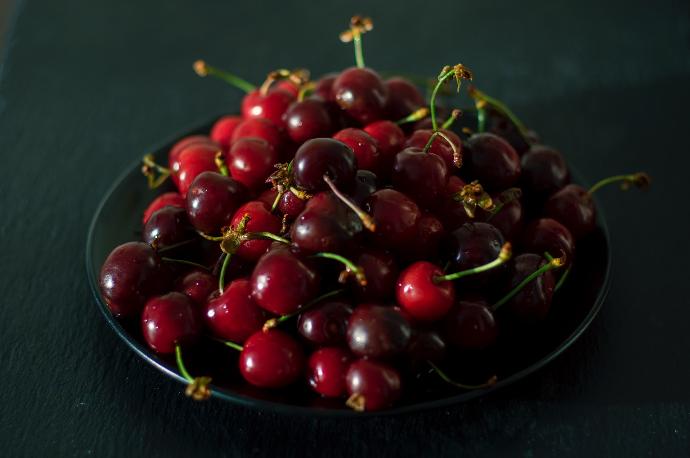 red cherries on black ceramic bowl